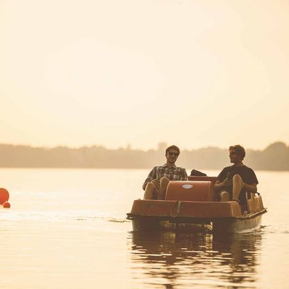 Zwei Freunde fahren am Abend mit dem Tretboot auf dem Plöner See