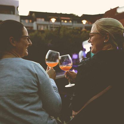 Zwei Freundinnen stoßen mit ihren Cocktails am Bootshafen an