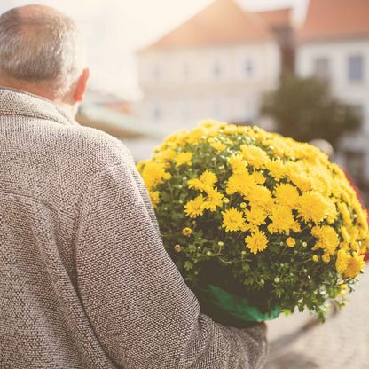 Mann hält Blumentopf auf dem Wochenmarkt im Arm