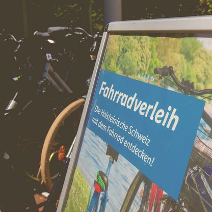 Ein Schild weist auf den Fahrradverleih an der Tourist Info Malente hin. 