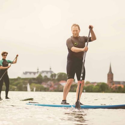 Zwei Stand-Up-Paddler mit dem Plöner Schloss im Hintergrund