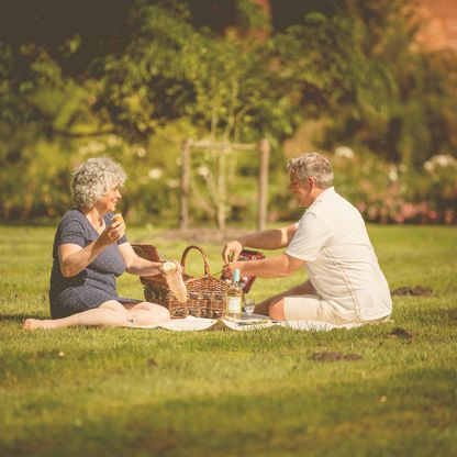 Paar sitzt auf einer Picknickdecke auf der Wiese direkt vor dem Eutiner Schloss