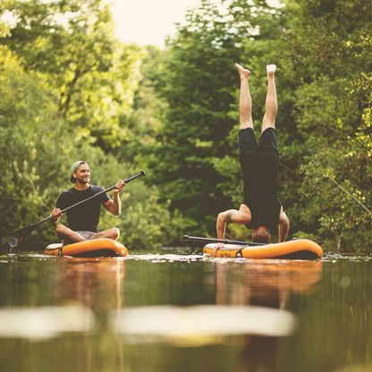 Ein Paddler macht einen Handstand auf einem SUP