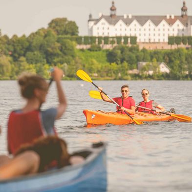 Kanuten begegnen sich auf dem Plöner See mit dem Schloss im Hintergrund