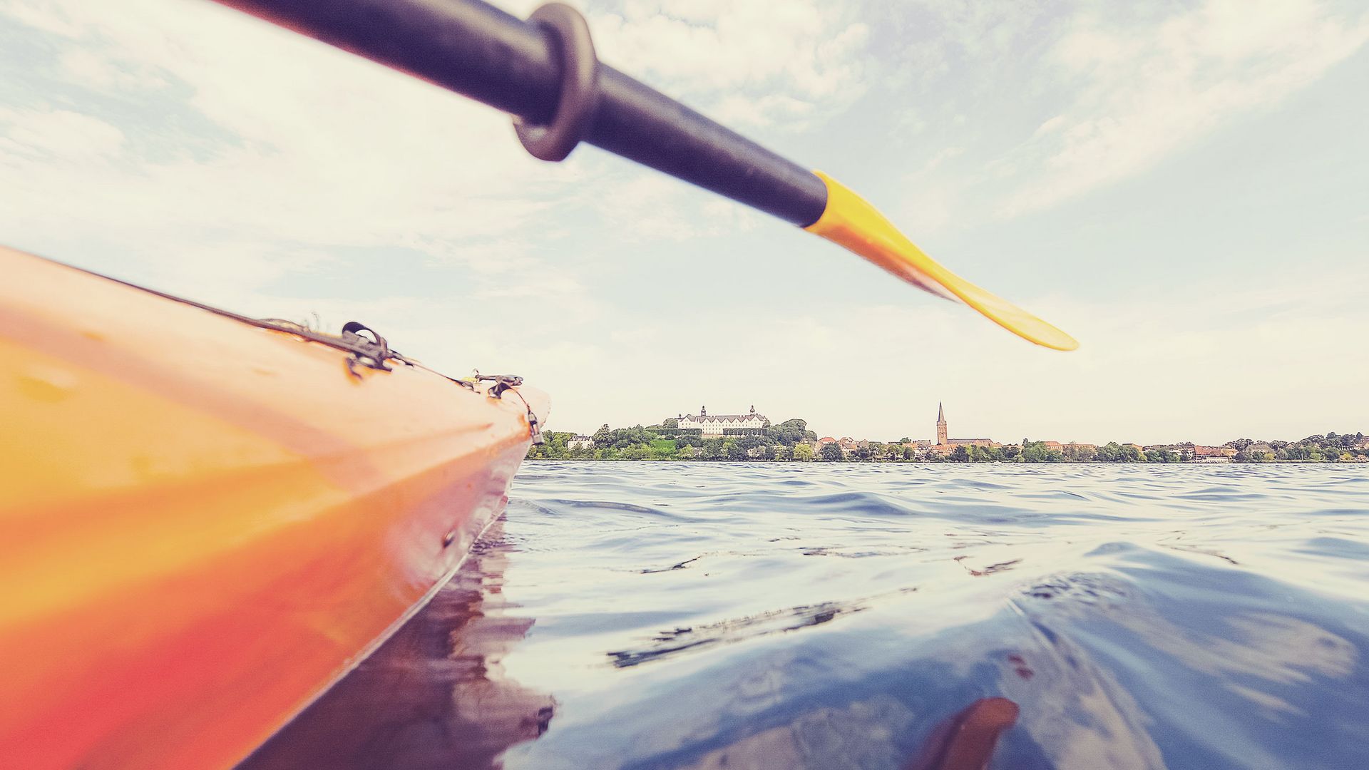 Kanustadtführung Plön: Paddel über dem Wasser mit Plöner Schloss im Hintergrund